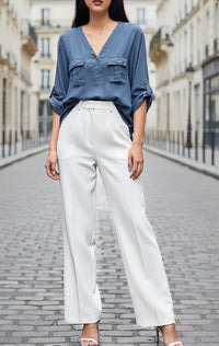 Woman wearing a blue shirt and white pants on a city street.