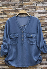 Blue shirt on a hanger against a stone wall background