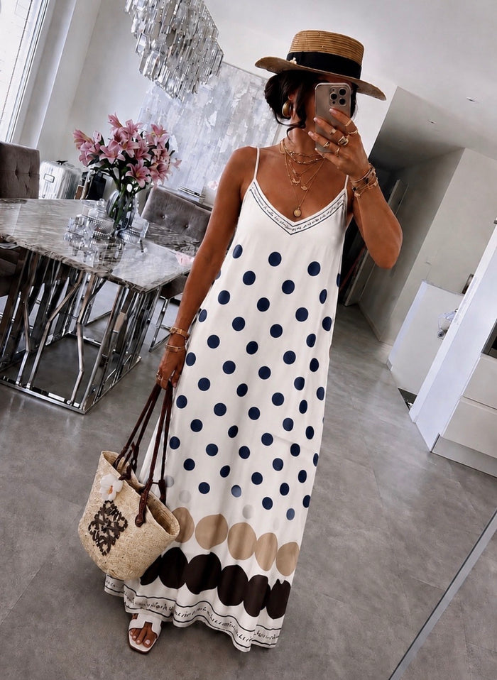 Woman in a polka dot dress taking a mirror selfie in a modern interior setting.