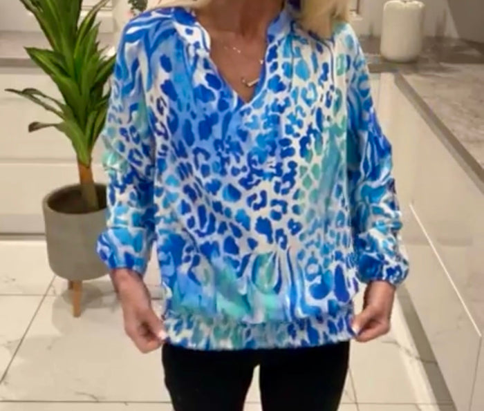 Person wearing a Belle Print Top in a room with a plant and tiled floor.