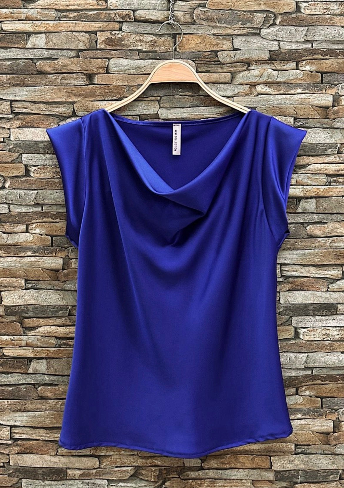 Blue top on a hanger against a stone wall background