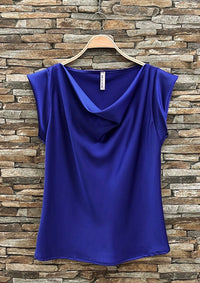 Blue top on a hanger against a stone wall background