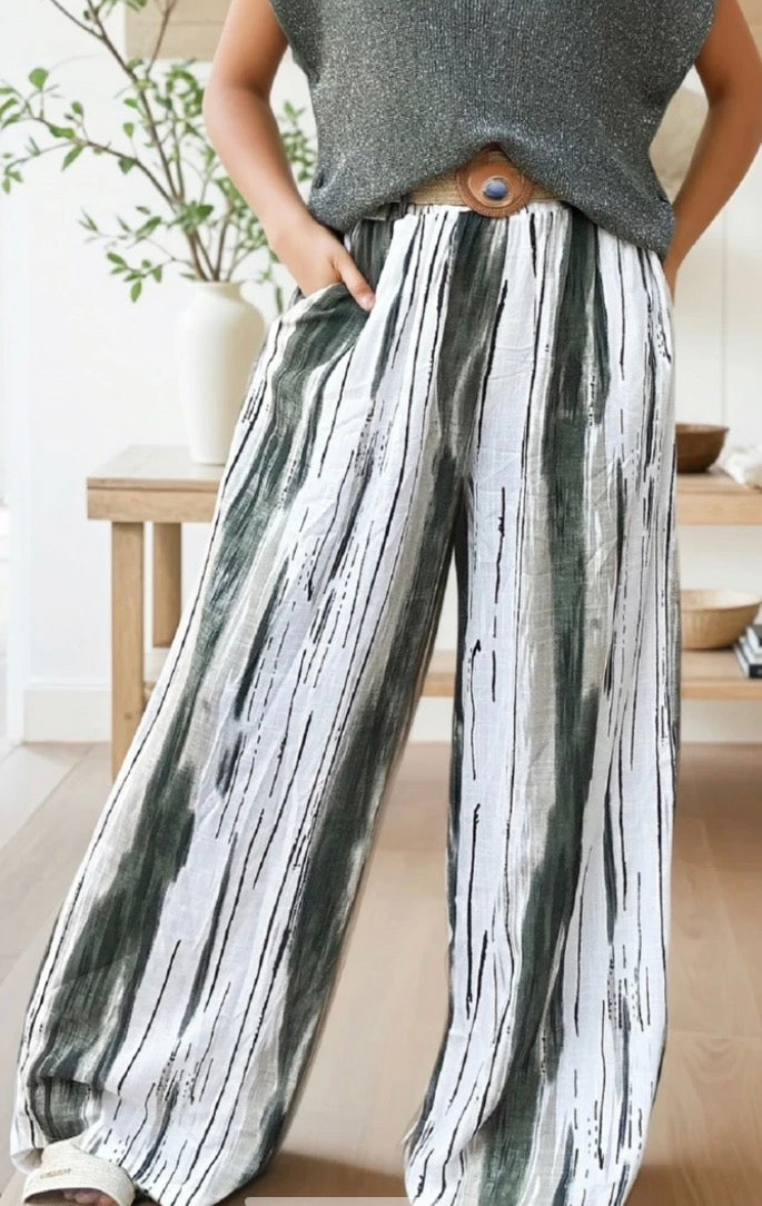 Person wearing a gray top and black and white patterned pants in a home setting.