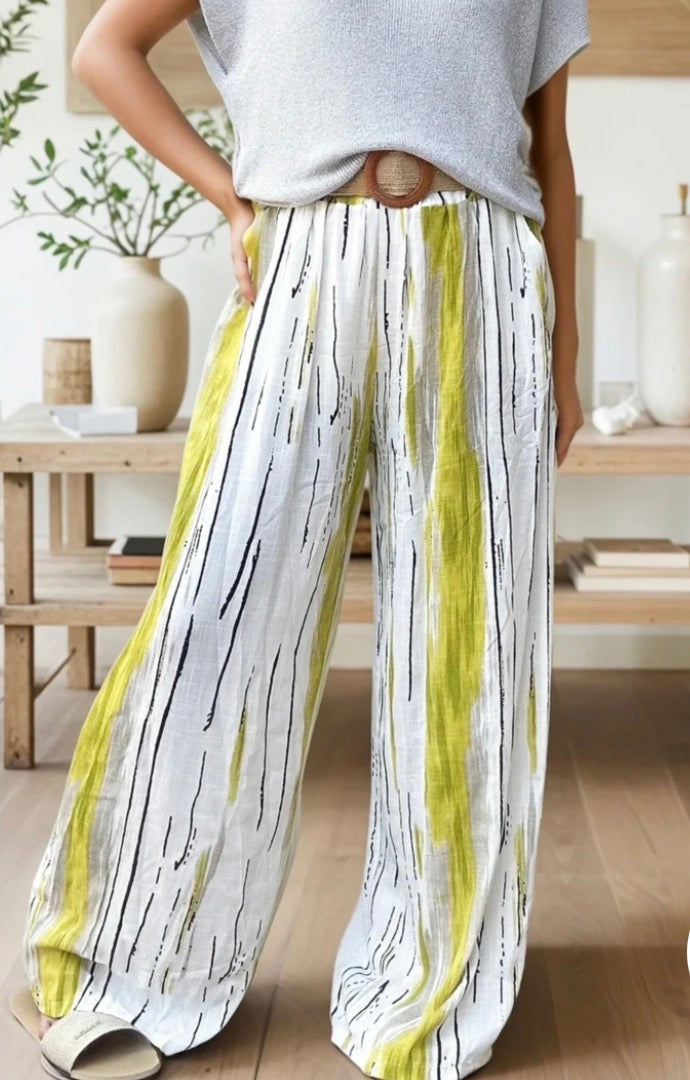 Person wearing a light gray top and white pants with black and yellow stripes indoors.
