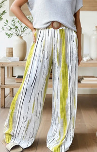 Person wearing a light gray top and white pants with black and yellow stripes indoors.