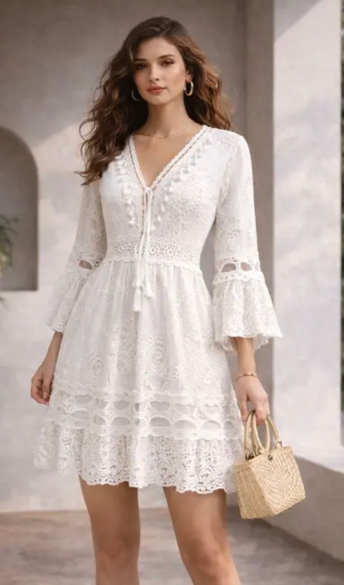 Woman wearing a white lace dress with long sleeves in an outdoor setting.