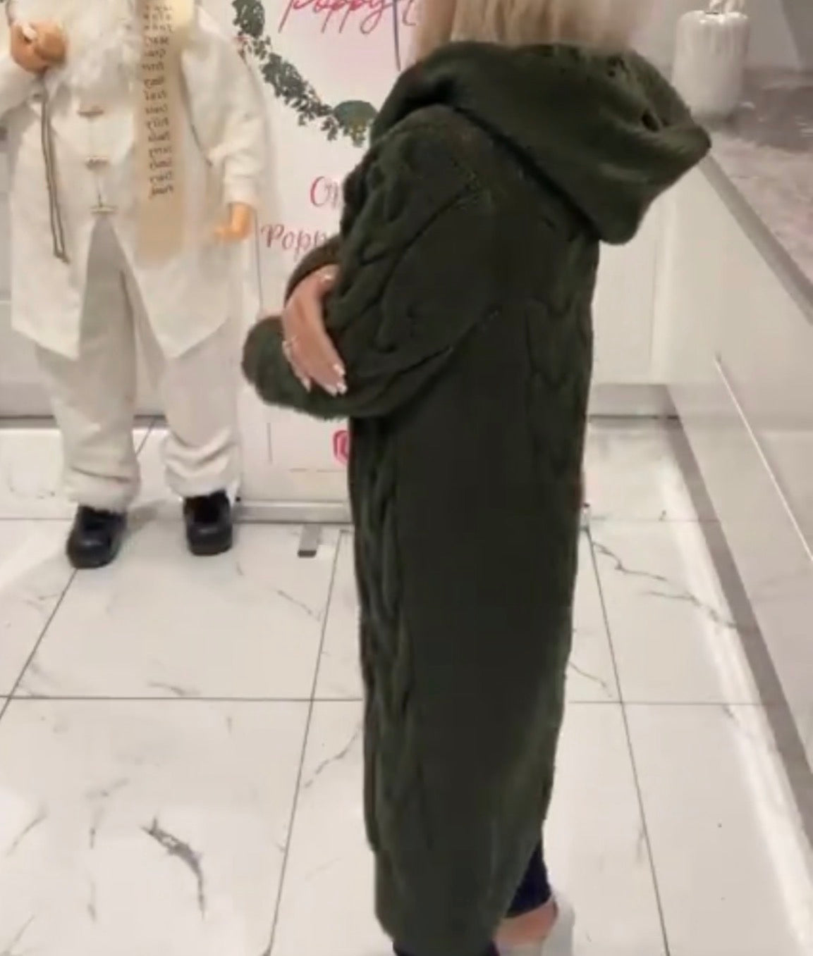 Person wearing a Gemma Hooded Cardigan in a store setting with mannequins in the background.