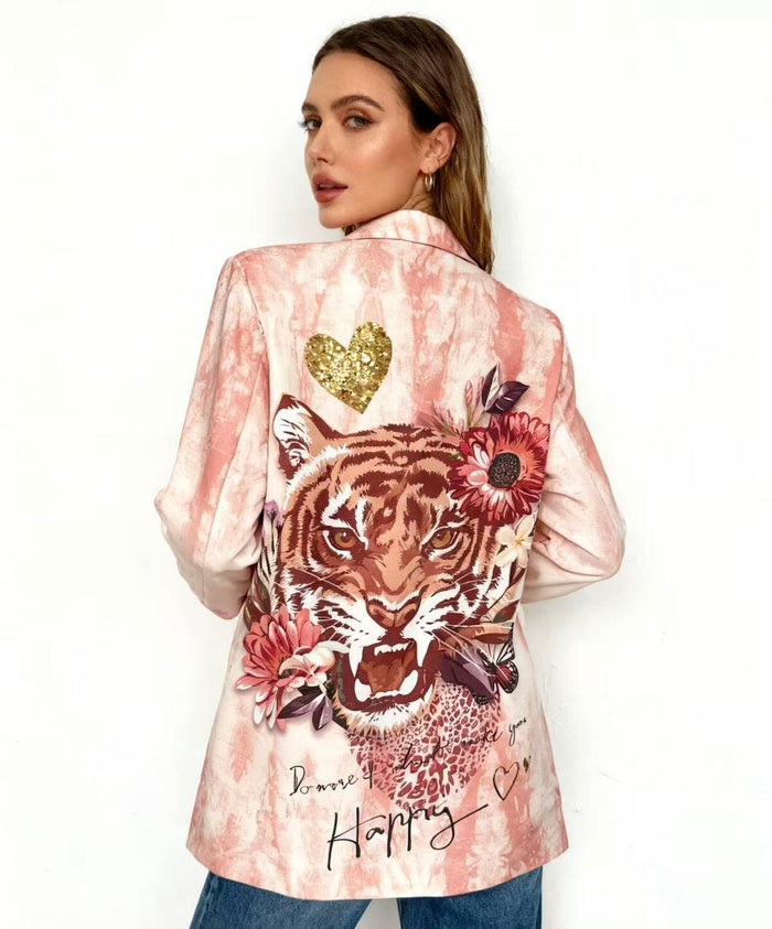 Woman wearing a pink satin jacket  name "Christina print blazer" with a tiger design and floral elements on a white background 