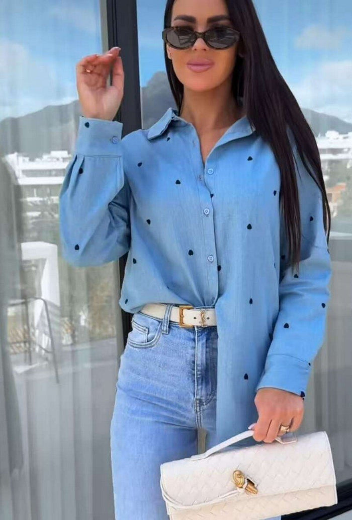 Woman wearing a Demi Denim Shirt with black polka dots and jeans, holding a white handbag.