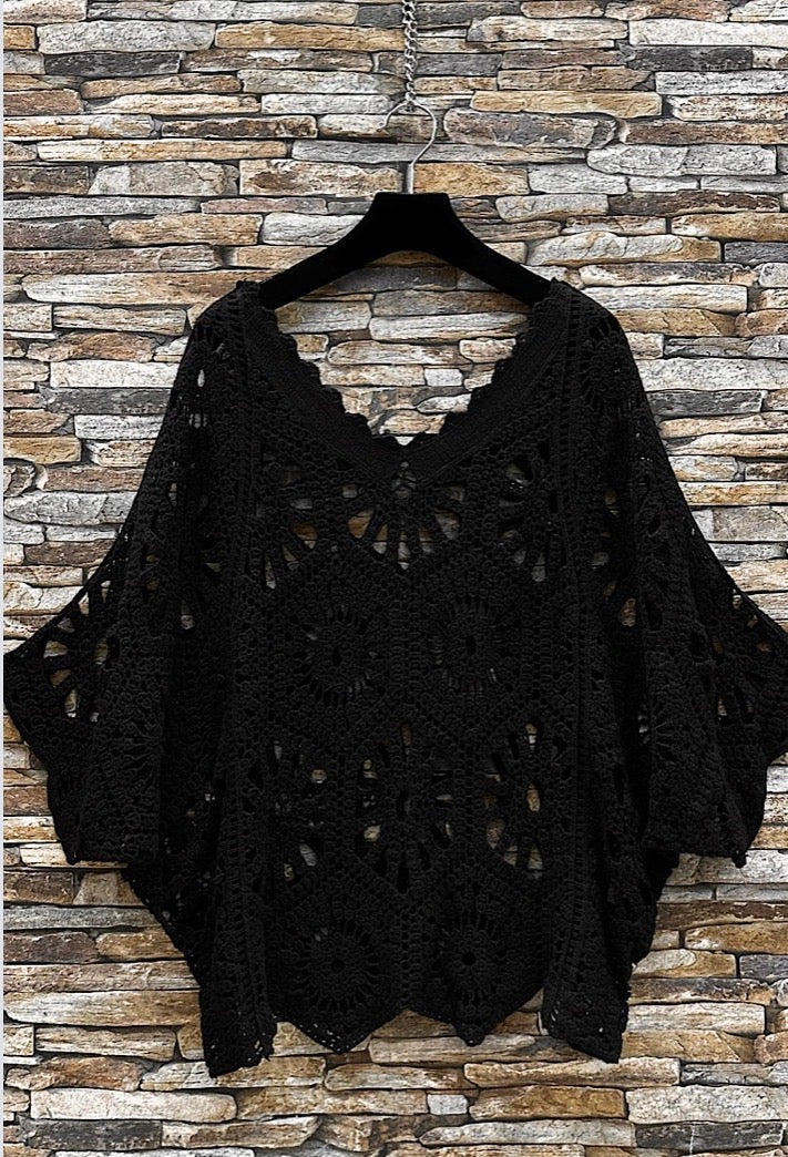 Black lace top on a hanger against a stone wall background
