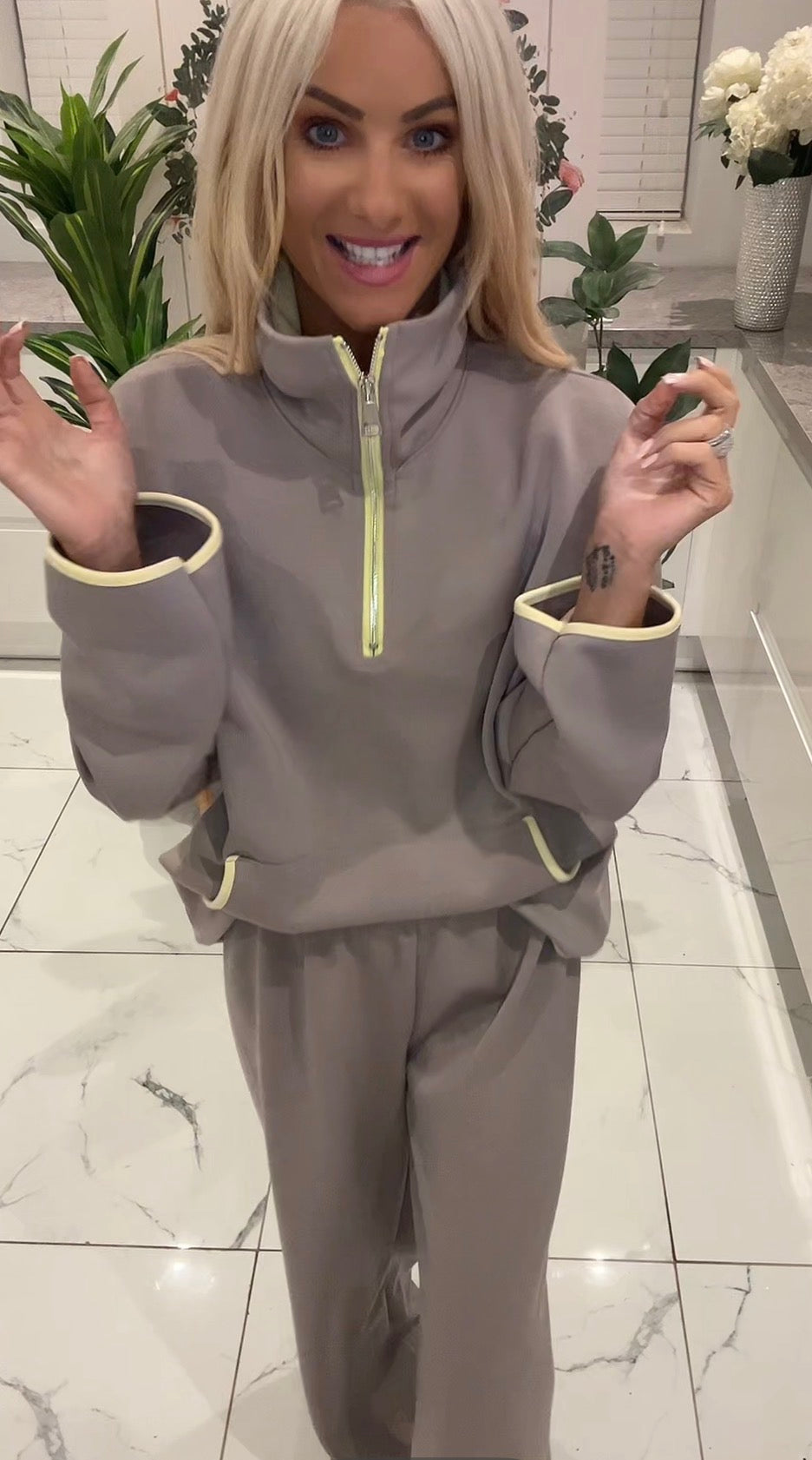 Woman wearing a gray tracksuit with yellow accents in an indoor setting.
