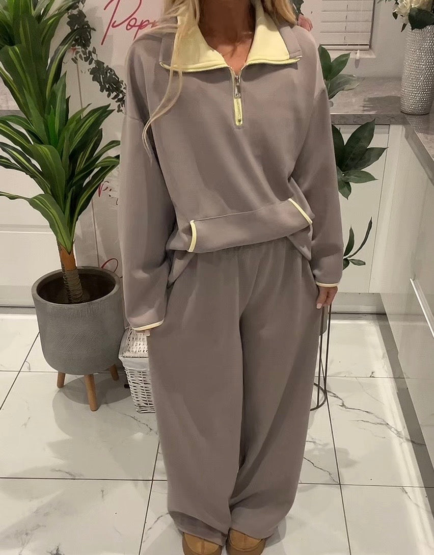 Person wearing a gray tracksuit in a room with plants and a white cabinet.