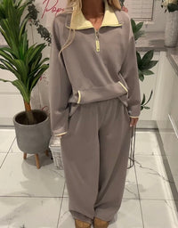 Person wearing a gray tracksuit in a room with plants and a white cabinet.
