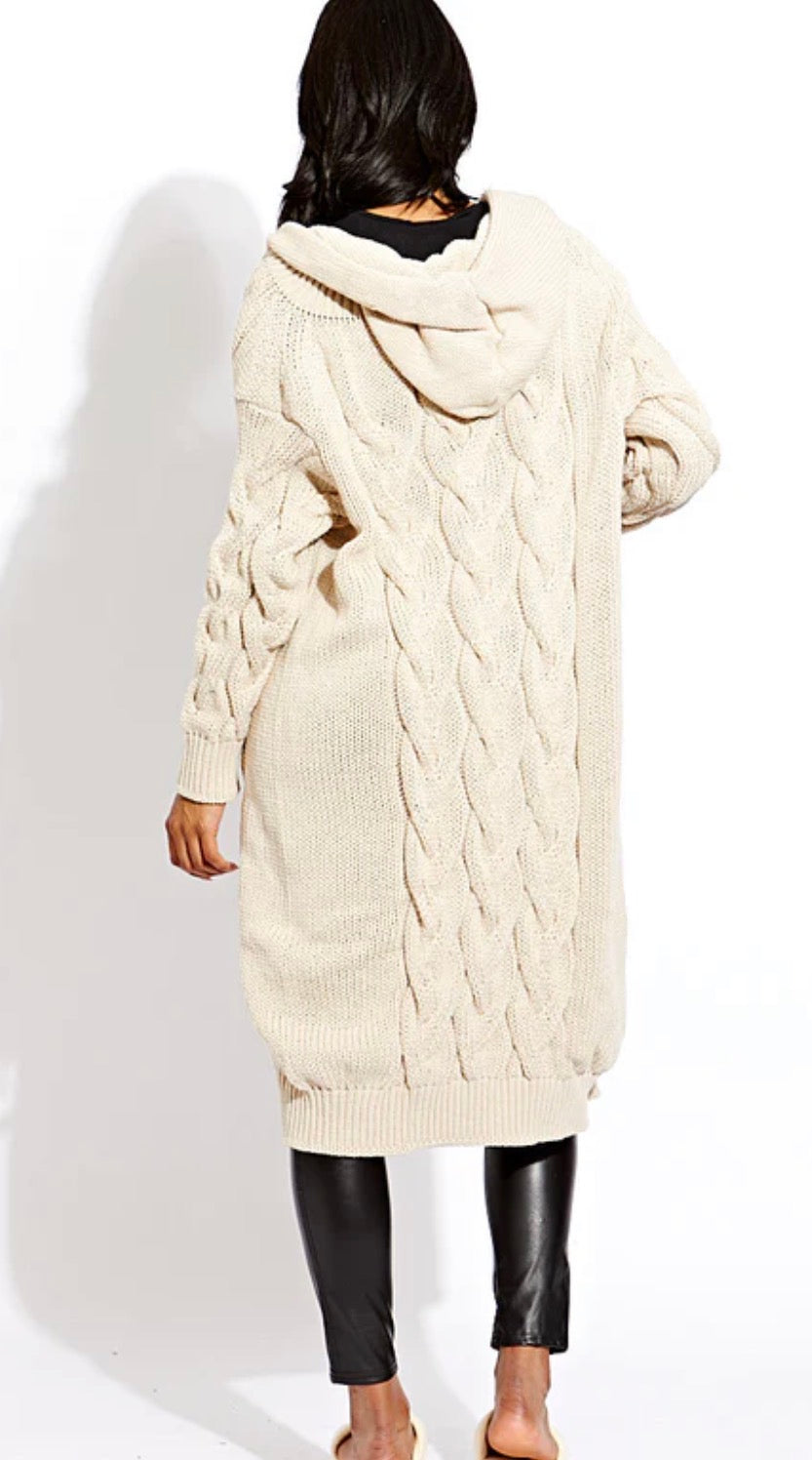 Person wearing a long cream cable knit cardigan on a white background