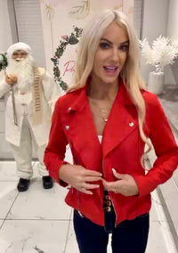 Woman in a Ivy Suede Detail Biker red Jacket  standing in a festive indoor setting with decorative elements.