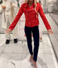 Person wearing a red Ivy Suede Detail Biker Jacket  and dark jeans standing in a store with a decorative background.