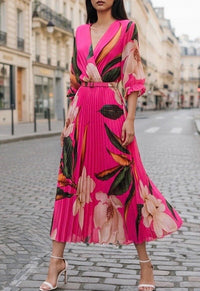 Woman wearing a vibrant pink floral dress on a city street.