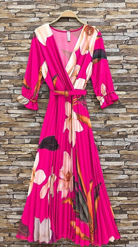 Pink floral dress on a hanger against a stone wall background