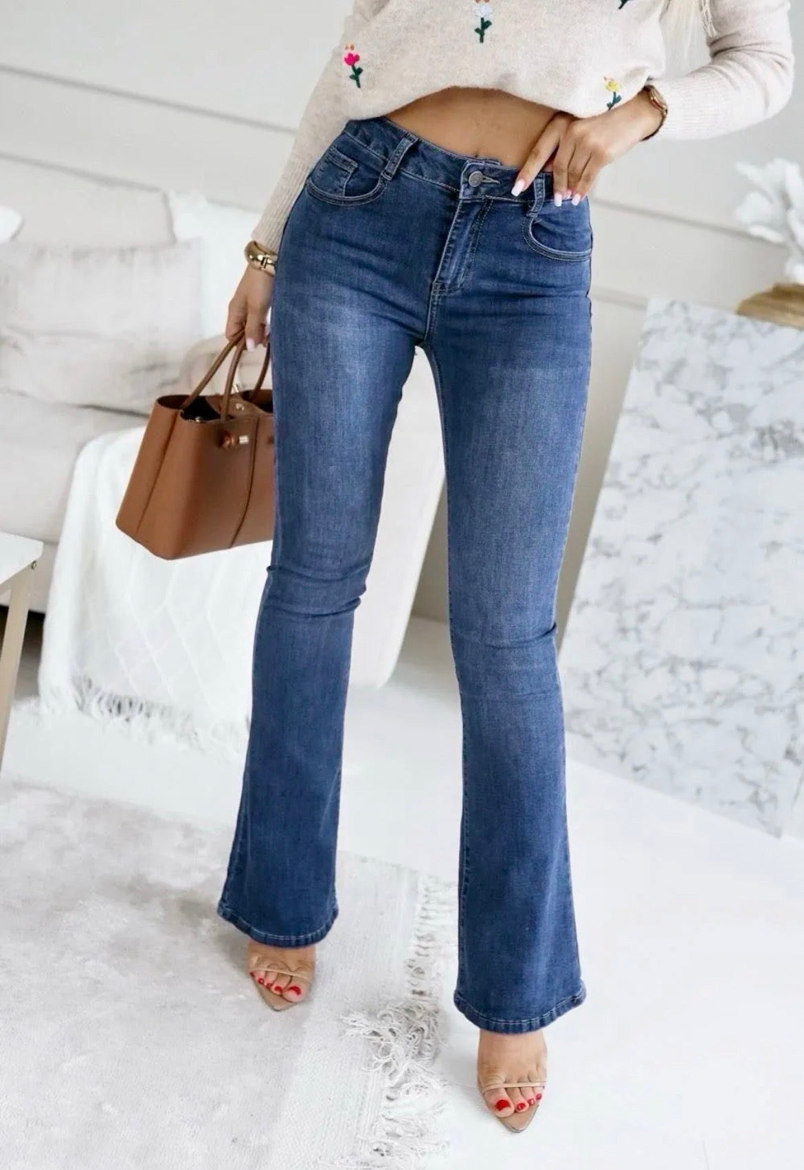 Person wearing Jemi Stretch Jeans and a white cropped sweater in a minimalistic room.