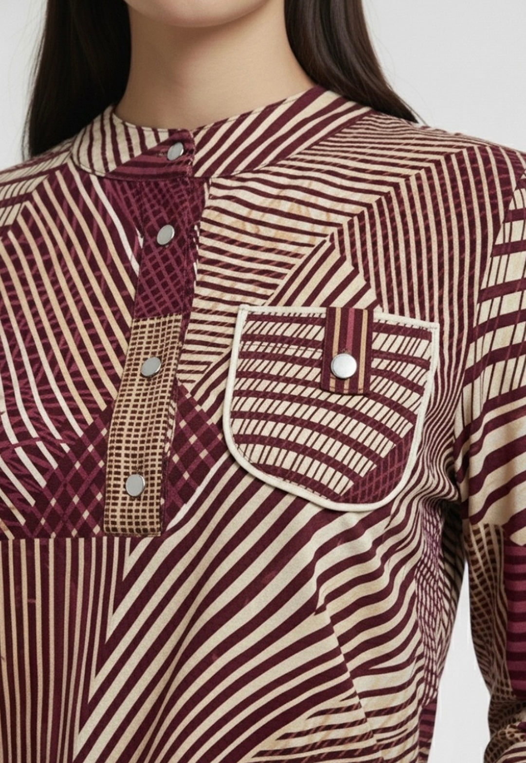 Close-up of a patterned shirt with maroon and beige colors on a plain background
