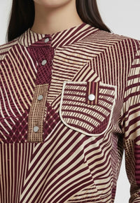 Close-up of a patterned shirt with maroon and beige colors on a plain background