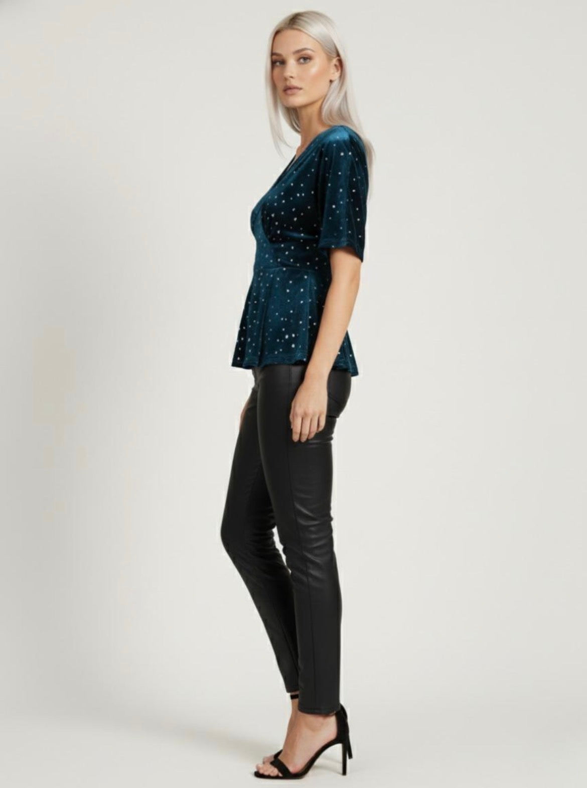 Woman wearing a dark blue sequin top and black pants on a white . Joyce Sparkle Detail V-Neck Top – Elegant Party Blousebackground