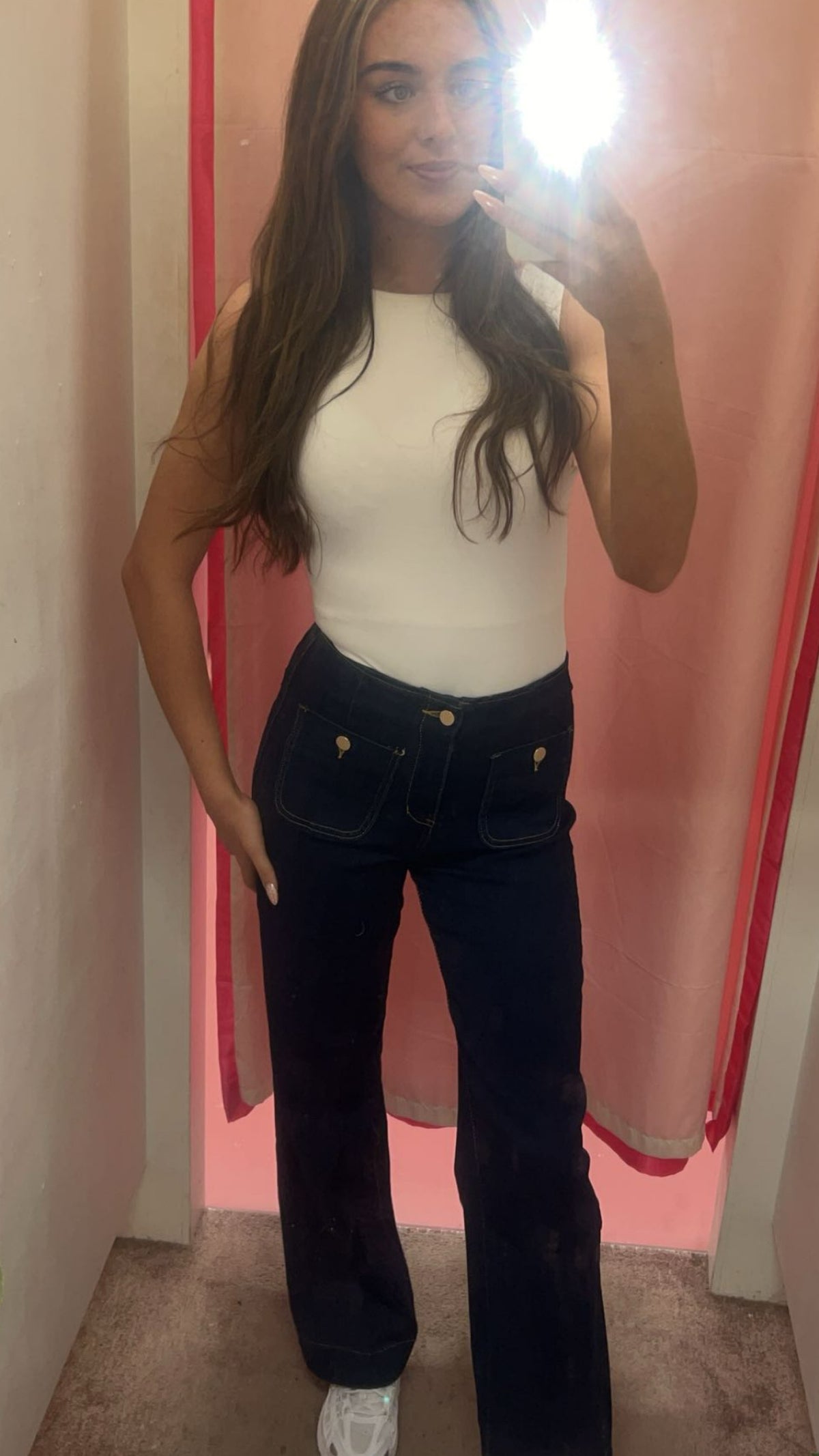 Woman taking a mirror selfie wearing a white tank top and dark Kacey Wide Leg Jean.
