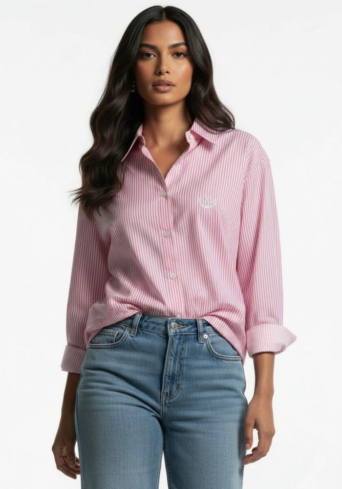 Woman wearing a pink Katrina Stripe Shirt and blue jeans on a white background