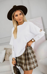 Woman wearing a Kelsey lace top with a black hat indoors.