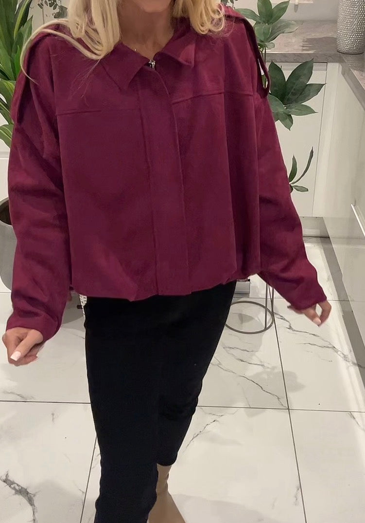 Person wearing a burgundy jacket and black pants indoors on a marble floor.