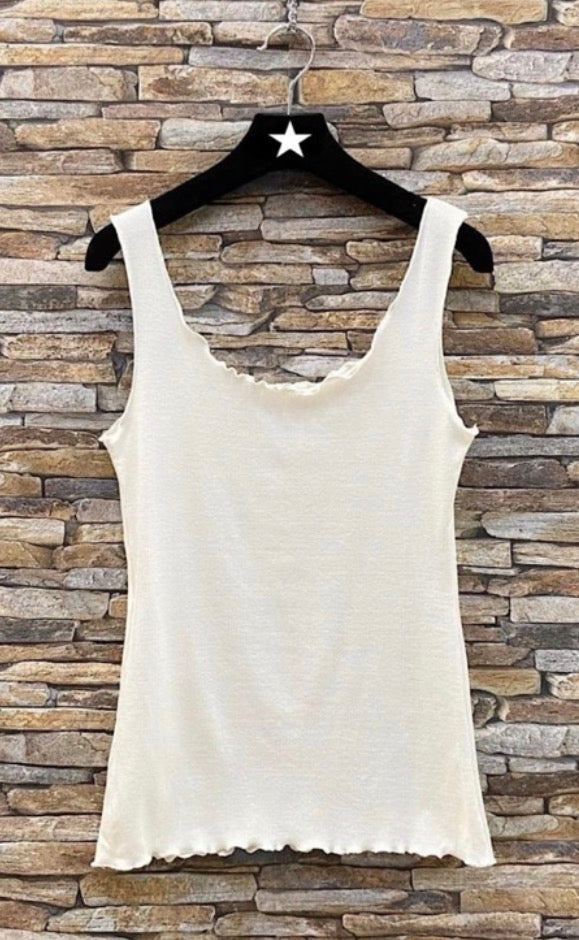 White tank Lettuce Ribbed Cami on a hanger against a stone wall background