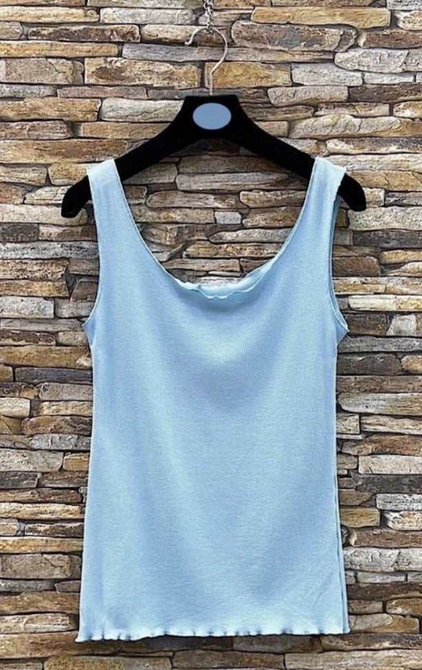 Light blue tank Lettuce Ribbed Cami  on a hanger against a stone wall background
