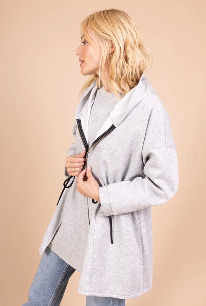 Woman wearing a gray cardigan against a beige background