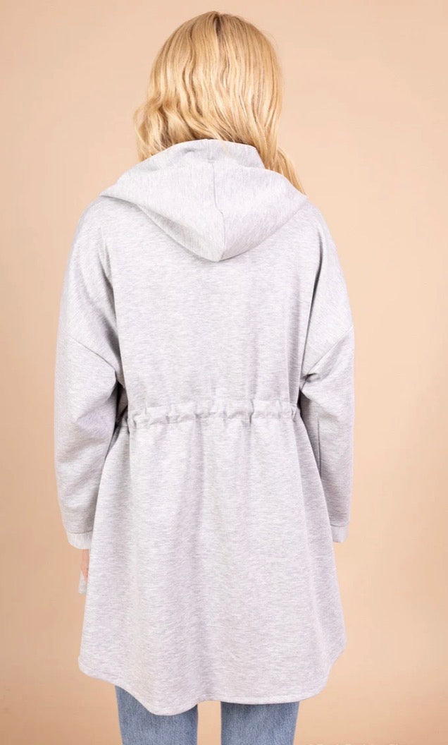 Person wearing a gray hooded coat on a beige background