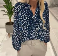 Person wearing a Lucinda Print Band Top with beige pants in an indoor setting.