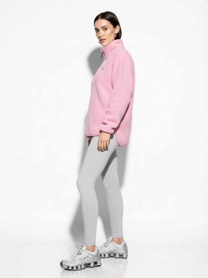 Woman wearing a pink jacket and gray leggings on a white background