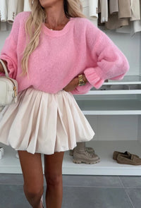 Person wearing a pink Marsha knit and white skirt in a store setting