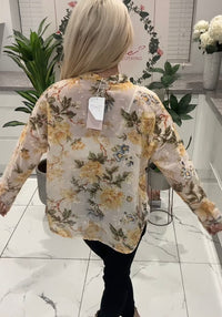 Person wearing a floral blouse with a tag in a store setting