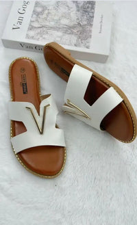 Pair of white sandals with brown soles on a light gray surface.