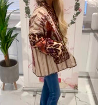 Person wearing a patterned Sadie Jacket Stylish Womens Jacket in an indoor setting with a plant and decorative items.