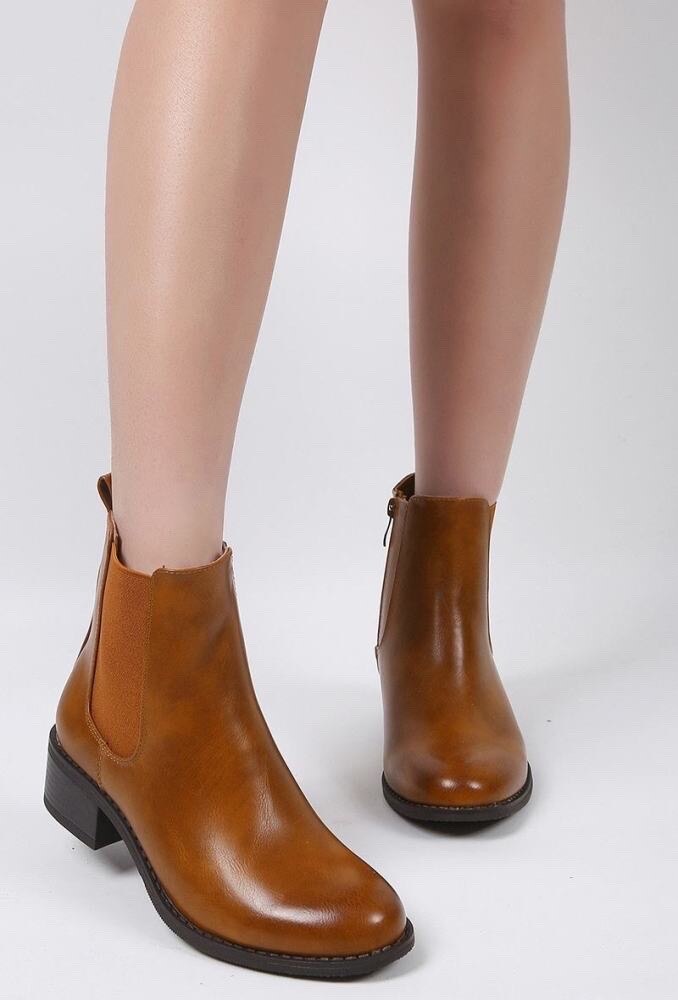 Brown leather ankle boots worn by a person on a white background