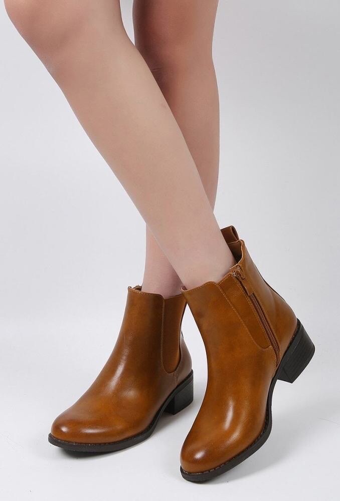 Brown ankle boots worn with beige tights on a white background