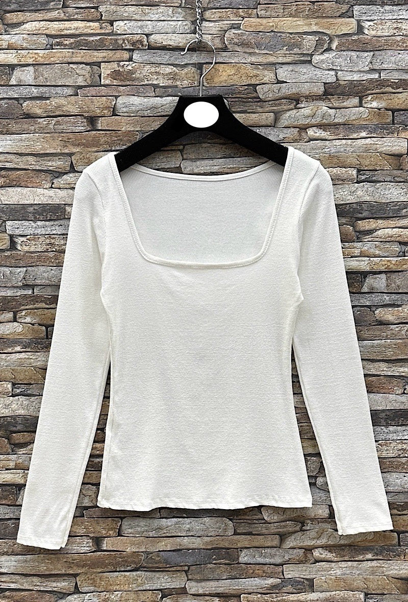 Susie Square Neck Basic Top White long-sleeve shirt on a hanger against a stone wall background