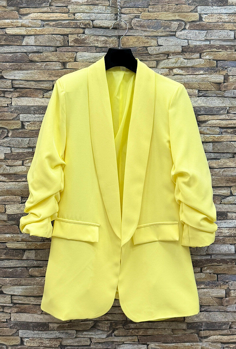 Yellow suit jacket on a hanger against a brick wall background