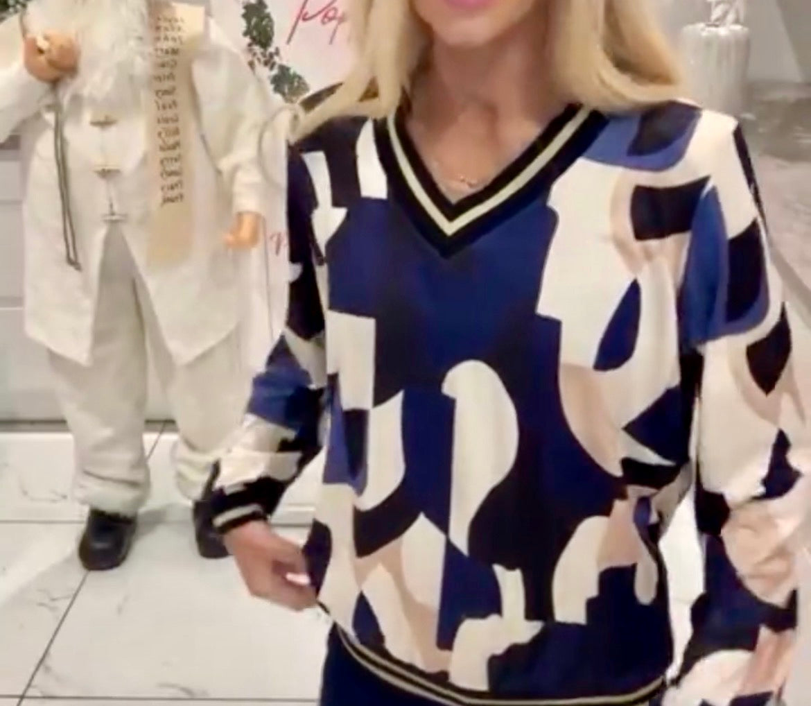 Person wearing a blue and white Cindy Metallic V-Neck Print Top with a blurred background